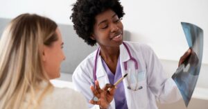 Médica residente ao lado de colega analisa radiografia durante atendimento
